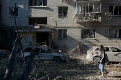 Une femme marche près d'un immeuble résidentiel endommagé à la suite d'une frappe à Kiev, le 20 août 2026 - © AFP - Tetiana DZHAFAROVA Une femme marche près d'un immeuble résidentiel endommagé à la suite d'une frappe à Kiev, le 20 août 2026 - © AFP - Tetiana DZHAFAROVA