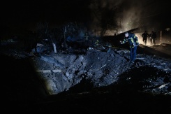 Un pompier ukrainien examine un cratère après une frappe de missile russe qui a touché des habitations à Kiev dans la soirée du 21 octobre 2026 - © AFP - Genya SAVILOV