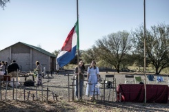 Une habitante d'Orania, Cara Tomlinson, hisse le drapeau de l'ancienne République sud-africaine au cimetière construit sur les lieux d'un camp de concentration de la guerre anglo-boer à Doornbult, près d'Orania, le 30 mai 2026. - © AFP - MARCO LONGARI