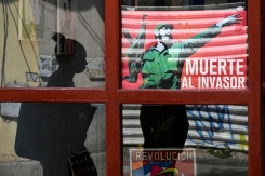 Une femme passe devant une affiche du défunt dirigeant cubain Fidel Castro sur laquelle on peut lire "Mort à l'envahisseur", à La Havane, le 13 mars 2026 - © AFP/Archives - YAMIL LAGE