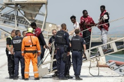 Des migrants débarquent du navire l'Argonaute ; ils ont été secourus en mer après que leur embarcation a pris feu lors d'une tentative de traversée de la Manche au port de commerce de Boulogne-sur-Mer, le 4 août 2026 - © AFP - Sameer AL-DOUMY