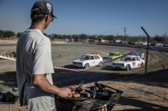 Un spectateur grille de la viande sur un braai (barbecue) devant une course de voiture sur l'ovale de terre de l'enclave afrikane en Afrique du Sud, le 30 mai 2026. - © AFP - MARCO LONGARI