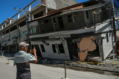 Un homme prend en photo un bâtiment effondré après un puissant séisme à General Santos, aux Philippines, le 9 juin 2026 - © AFP - Jam STA ROSA