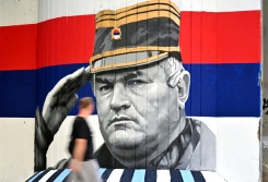 Un homme passe devant une fresque murale représentant l'ancien chef militaire des Serbes de Bosnie, Ratko Mladić, le 6 septembre 2026 à Belgrade, en Serbie, dont l'inhumation est prévue le 7 septembre 2026 au cimetière de Topčider à Belgrade, sur fond de critiques de l'UE concernant la "glorification" d'un criminel de guerre condamné pour génocide - © AFP - OLIVER BUNIC Un homme passe devant une fresque murale représentant l'ancien chef militaire des Serbes de Bosnie, Ratko Mladić, le 6 septembre 2026 à Belgrade, en Serbie, dont l'inhumation est prévue le 7 septembre 2026 au cimetière de Topčider à Belgrade, sur fond de critiques de l'UE concernant la "glorification" d'un criminel de guerre condamné pour génocide - © AFP - OLIVER BUNIC