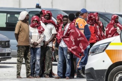 Des migrants attendent après avoir débarqué d'un navire, après leur sauvetage en mer alors que leur embarcation avait pris feu lors d'une tentative de traversée de la Manche, au port de commerce de Boulogne-sur-Mer, le 4 août 2026 - © AFP - Sameer AL-DOUMY