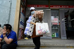 Une femme sort d'un supermarché après avoir acheté des produits de première nécessité, le 25 avril 2022 à Pékin - © AFP - Jade GAO