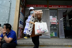 Une femme sort d'un supermarché après avoir acheté des produits de première nécessité, le 25 avril 2022 à Pékin - © AFP - Jade GAO Une femme sort d'un supermarché après avoir acheté des produits de première nécessité, le 25 avril 2022 à Pékin - © AFP - Jade GAO