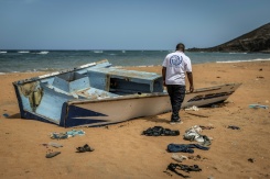 Un membre de l'Organisation internationale pour les Migrations (OIM), sur la plage de Gehere à Djibouti, près des restes d'une embarcation transportant des migrants et ayant fait récemment naufrage - © AFP - Luis TATO