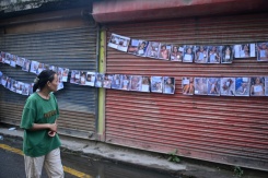 Une femme regarde les photos de personnes mortes ou disparues dans la crue destructrice qui a fait au moins 633 morts à la frontière entre le Népal et la Chine, le 29 août 2026 à Katmandou - © AFP - PRAKASH MATHEMA