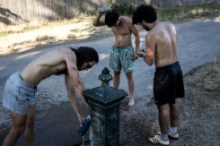 Des gens remplissent leur gourde et s'aspergent d'eau, le 11 juillet 2026 au bois de Vincennes, à Paris - © AFP - Behrouz MEHRI