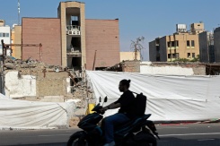Un motocycliste passe devant le lycée Alameh Tabatabaei, détruit par une frappe aérienne américano-israélienne pendant la guerre, à Téhéran, le 3 mai 2026 - © AFP - -