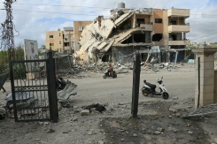 Un homme passe en moto devant un bâtiment abritant une ONG, détruit par une frappe israélienne, dans la ville de Tyr, dans le sud du Liban, le 15 mai 2026 - © AFP - Kawnat HAJU