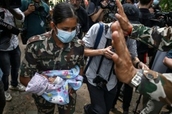 Une militaire porte un enfant secouru après la crue destructrice qui a fait au moins 633 morts à la frontière entre le Népal et la Chine, le 29 août 2026 au camp de Trishuli, dans le district népalais de Nuwakot   - © AFP - Arun SANKAR